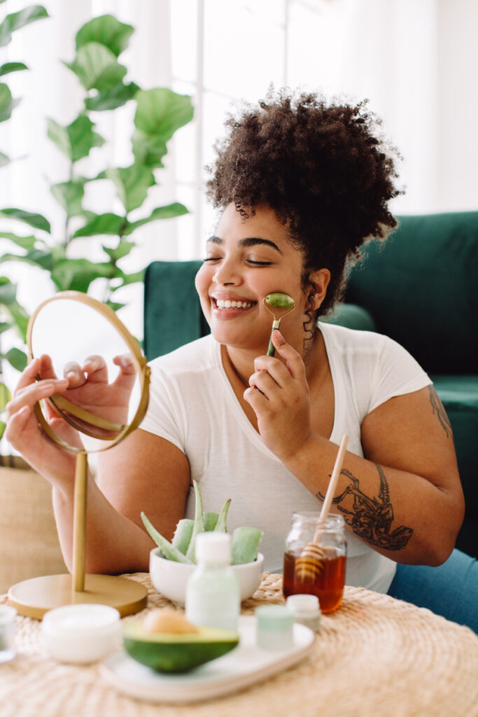 Pretty female using jade roller on face skin for smoothing at home. Woman doing self beauty care treatment at home.