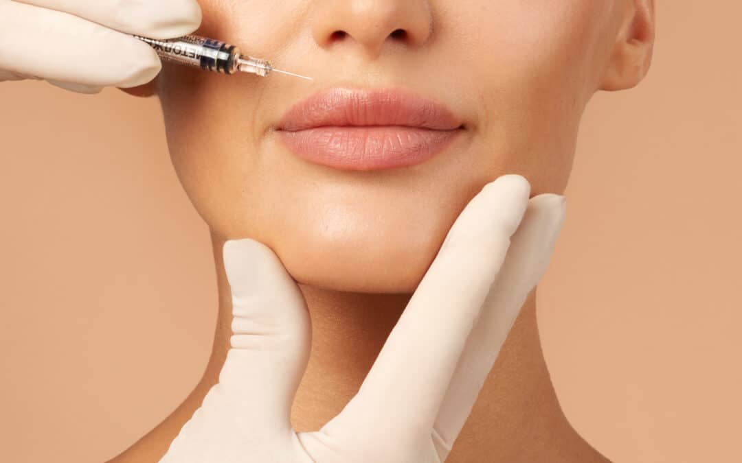 Lip injections concept. Young lady getting beauty injection in her lips, beautician holding syringe with filler next to woman mouth, cropped